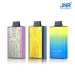 Three JNR MEGA BOX disposable vapes with 25,000 puff capacity; two with embossed "Skull King" engravings in silver and gold, and one with a gradient yellow-blue finish labeled "Strawberry Raspberry Ice"